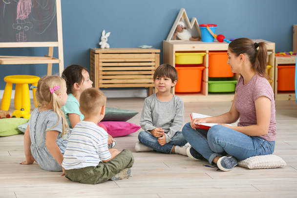 Nursery teacher with cute little children in kindergarten - Photo, Image