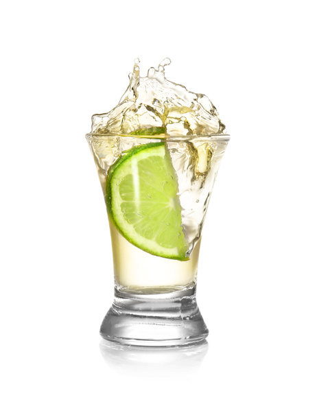 Dropping of lime into glass with tasty tequila on light background - Photo, Image