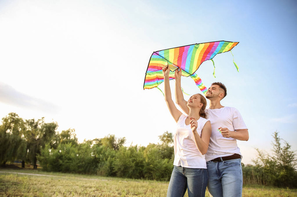 Young couple flying kite outdoors - Φωτογραφία, εικόνα