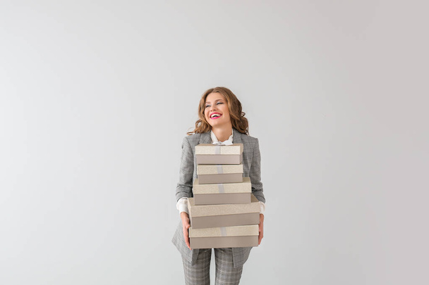 Beautiful young businesswoman with gift boxes on light background - Fotoğraf, Görsel