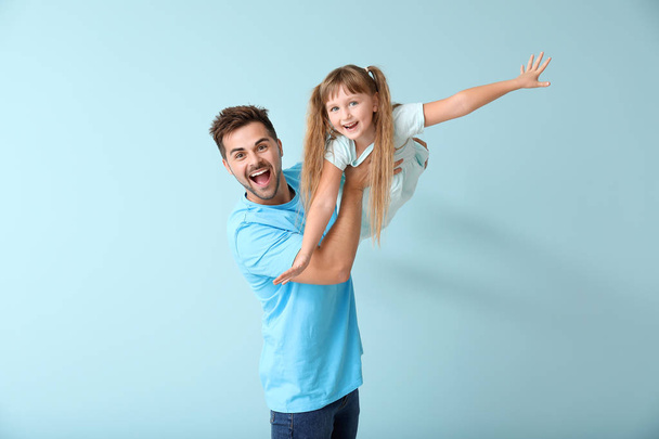 Happy father playing with daughter on color background - Photo, Image