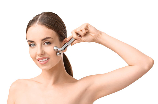 Mulher bonita com ferramenta de massagem facial no fundo branco
 - Foto, Imagem