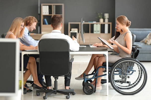 Giovane donna handicappata con colleghi che lavorano in ufficio
 - Foto, immagini