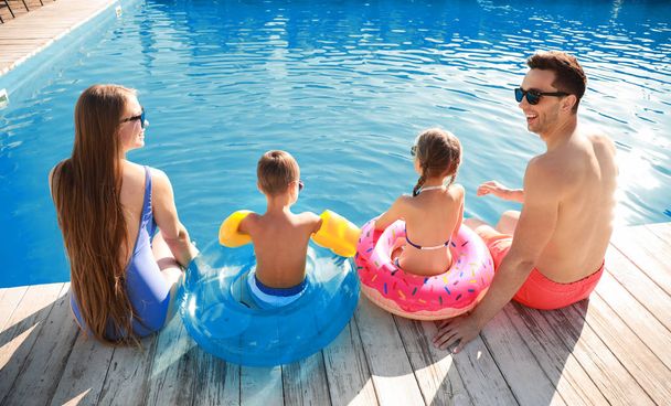 Young family sitting near swimming pool, back view - Photo, Image