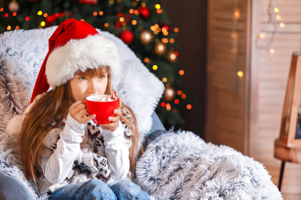 Klein meisje drinkt warme chocolademelk thuis op kerstavond - Foto, afbeelding