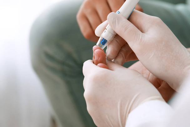 Doctor taking blood sample of diabetic man in clinic, closeup - Fotografie, Obrázek