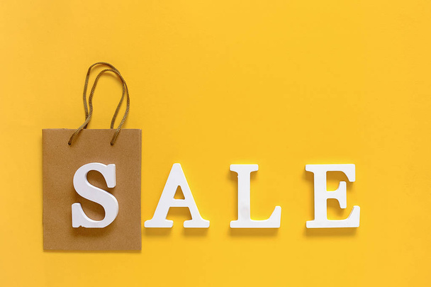 Text SALE from white volume letters and blank shopping bag on yellow background. Top view Flat lay Copy space Concept discount. Creative template for your text, design, ad or advertisement - Foto, Imagem