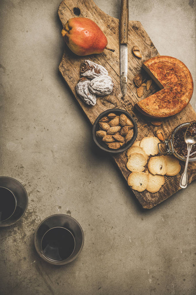 Wine and snack set. Flat-lay of two glasses of red wine, vintage corkscrews, cheese and appetizers on wooden board over dusty concrete background, top view, copy space. Party food concept - 写真・画像