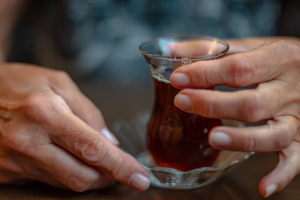 Hands of the elderly woman who holds a glass with tea - Foto, Imagem