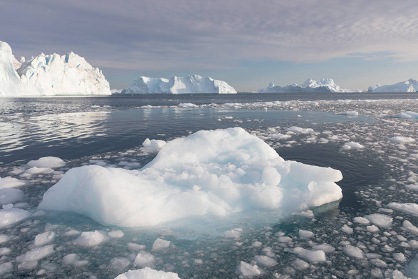 Natur und Landschaft Grönlands oder der Antarktis. Reisen auf dem Schiff zwischen Eis. Untersuchung eines Phänomens der globalen Erwärmung Eis und Eisberge ungewöhnlicher Formen und Farben schönen sonnigen und bewölkten Tag  - Foto, Bild