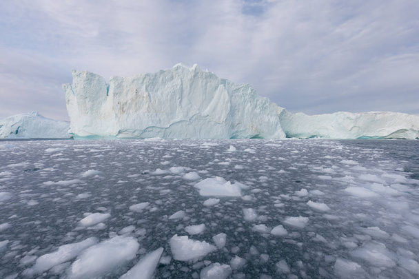 グリーンランドや南極の自然と風景。氷の間で船に乗る。地球温暖化の現象を研究し、異常な形と色の氷山美しい晴れと曇りの日  - 写真・画像