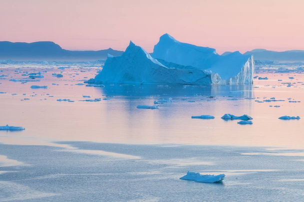 Grönland icefjord buzdağları ile Arktik doğa manzara gece yarısı güneş günbatımı / ufukta gündoğumu ile. Gece yarısı sezonunda erken sabah yaz alpenglow. Ilulissat, Batı Grönland. - Fotoğraf, Görsel