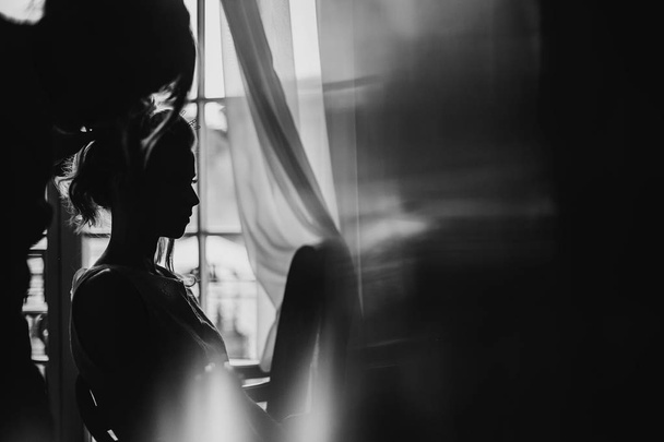 Silhouette of beautiful happy bride getting her hair done by pro - Fotografie, Obrázek