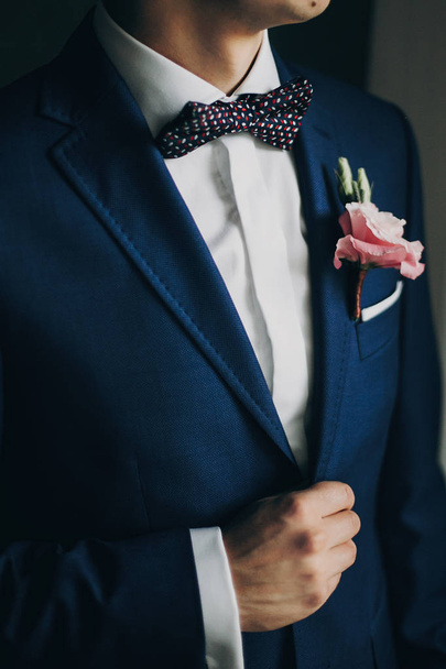 stilvoller Bräutigam im blauen Anzug, mit Fliege und Boutonniere mit Pi - Foto, Bild