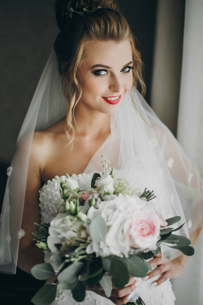 stilvolle Braut mit modernem Brautstrauß und posiert in weicher  - Foto, Bild