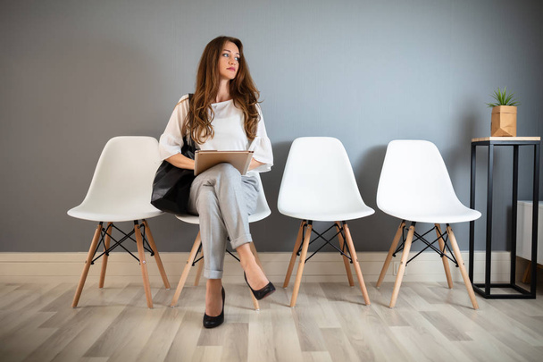 Young Businesswoman Holding Folder While Sitting On Chair Waiting For Job Interview - Fotografie, Obrázek