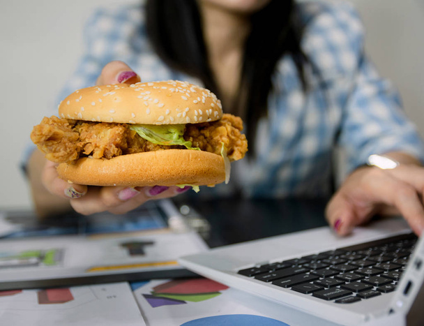Women work and eat hamburgers to eat lunch in office - Fotoğraf, Görsel