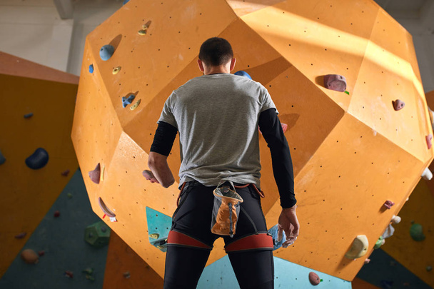 Low angle back view of physically impaired sportsman staring at climbing wall - Fotoğraf, Görsel