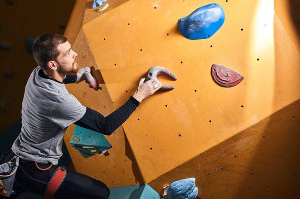 Physically challenged man climbing on artificial colourful rock wall - Фото, зображення