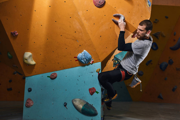 Handsome athletic boulderer training hard at indoor climbing settings - Photo, image