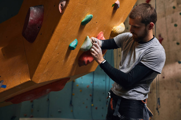 Physically challenged boulderer fixing artificial rocks and holds at climbing wall - Fotó, kép