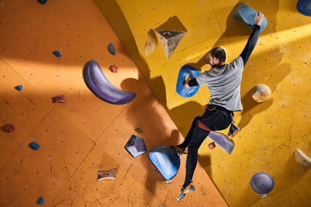 Physically challenged man stuck at difficult rock wall in bouldering gym - Photo, image