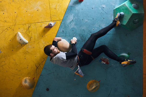 Motivated physically challenged boulderer with beard hanging at climbing wall - Foto, Bild