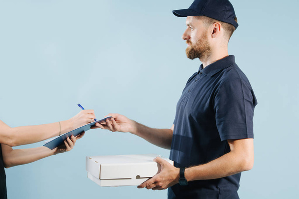 Woman hand accepting a box delivery from a courier, signing paper form with pen - Photo, Image