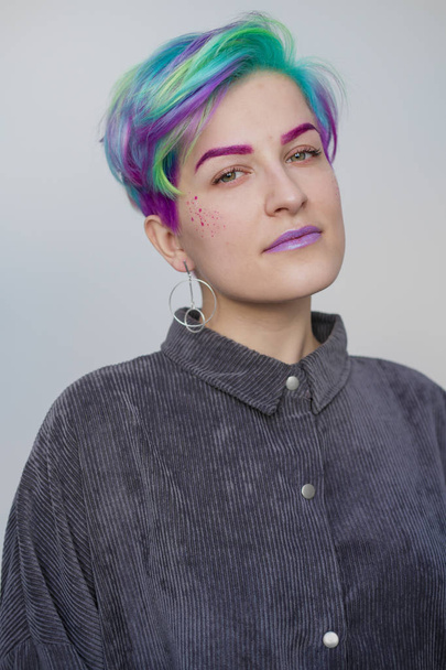 Young beautiful woman with dyed blue and green hair. Pixie bob short haircut The concept of hair styling. - Valokuva, kuva