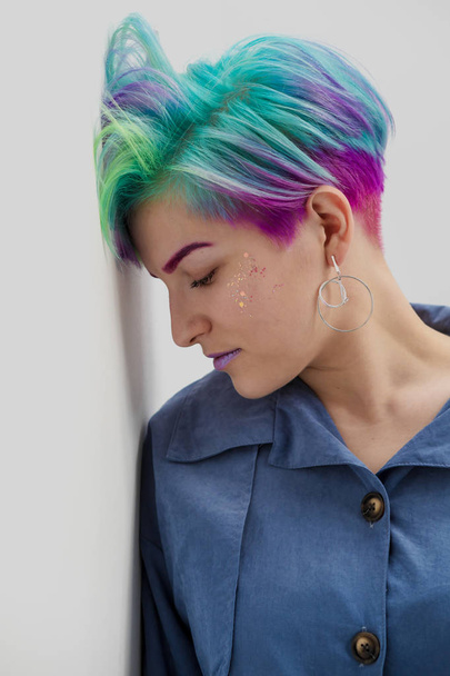 Young beautiful woman with dyed blue and green hair. Pixie bob short haircut The concept of hair styling. - Фото, изображение