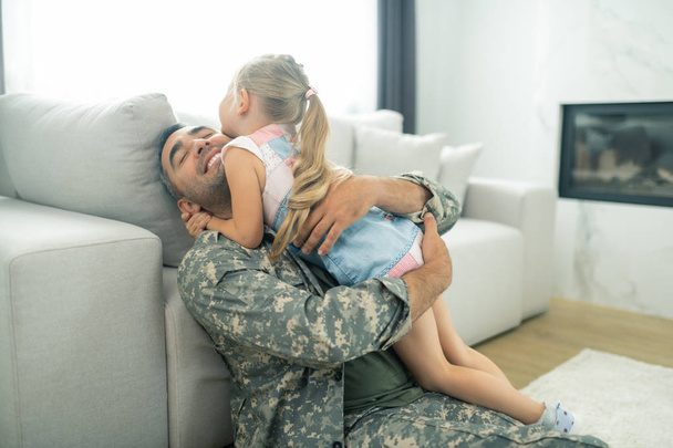 Happy military officer hugging his cute daughter tight - Foto, afbeelding
