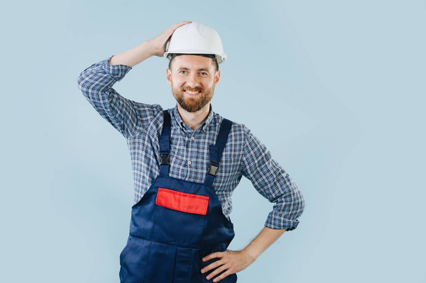 Confident construction worker in a white helmet and blue overalls - Φωτογραφία, εικόνα