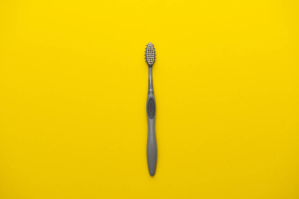 Uma escova de dentes cinza para dentes em um fundo amarelo
. - Foto, Imagem