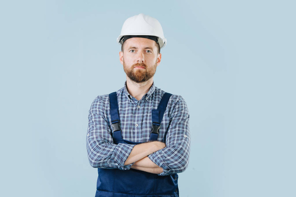 Confident construction worker in a white helmet and blue overalls - Foto, immagini