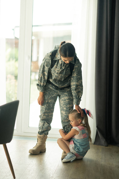 Dark-haired woman serving in armed forces touching her lovely daughter - Foto, Imagem