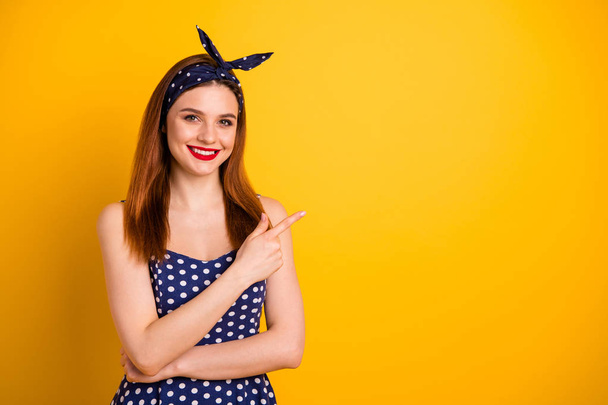 Photo of beautiful foxy lady indicate empty space low prices wear dotted dress headband isolated yellow background - 写真・画像