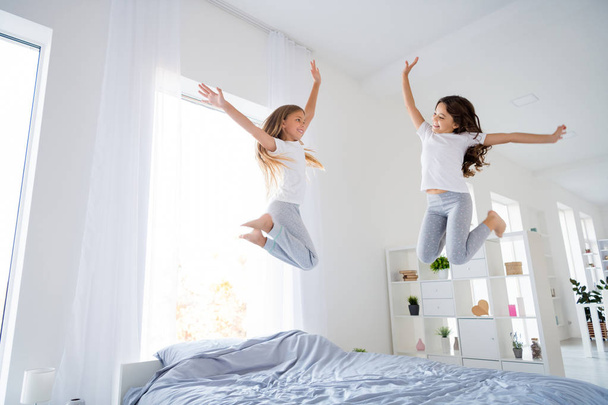 Low angle photo of cute sweet kid blonde brunette jumping look raise hands feel content room indoors apartment - Foto, Imagen
