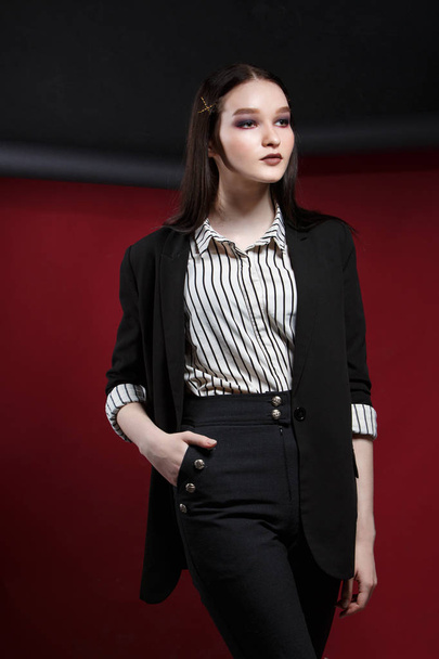 Young beautiful female fashion model in a business stylish suit on a red and black background. - Foto, Imagem