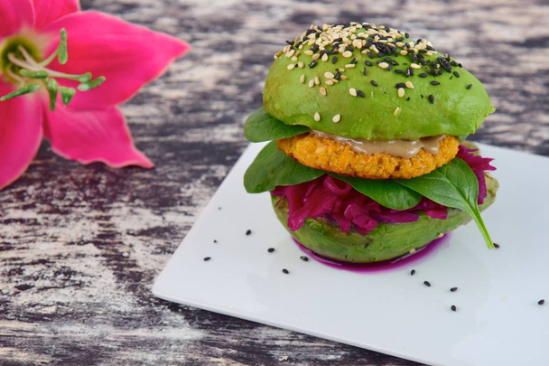 Healthy vegan avocado burger with red cabbage, spinach, chickpea cauliflower patties and tahini sprinkled with sesame seeds. - Foto, Imagem