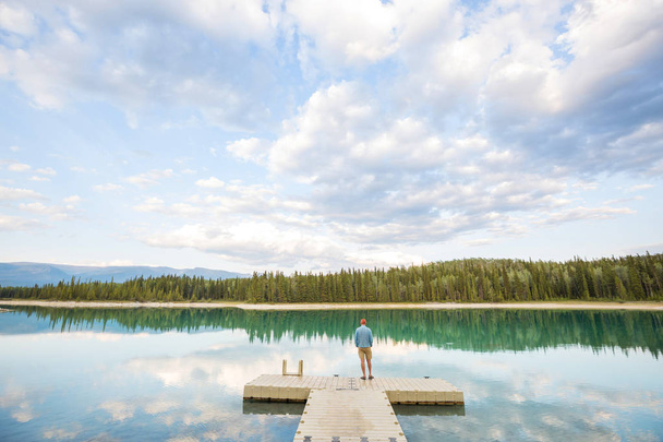 Spokojna scena nad jeziorem w Kanadzie z odbiciem skał w spokojnej wodzie. - Zdjęcie, obraz