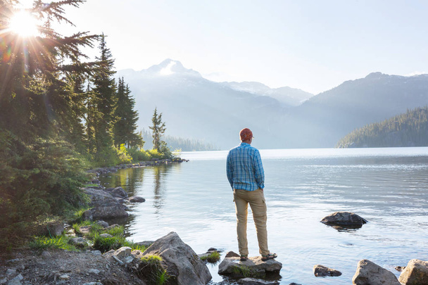 Hiker relaxing at serene mountain lake - Фото, изображение