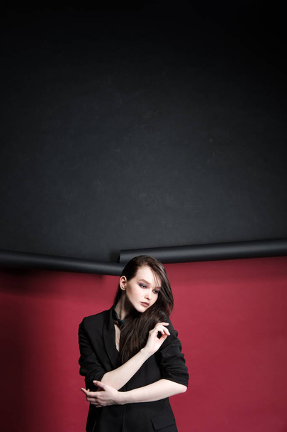 Jeune belle mannequin féminine dans un costume élégant d'affaires sur un fond rouge et noir
. - Photo, image