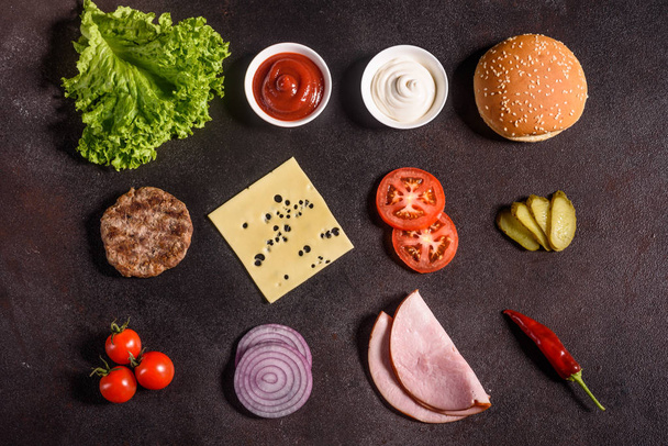 Ingredientes de hamburguesa en el fondo oscuro. Vista superior
 - Foto, imagen