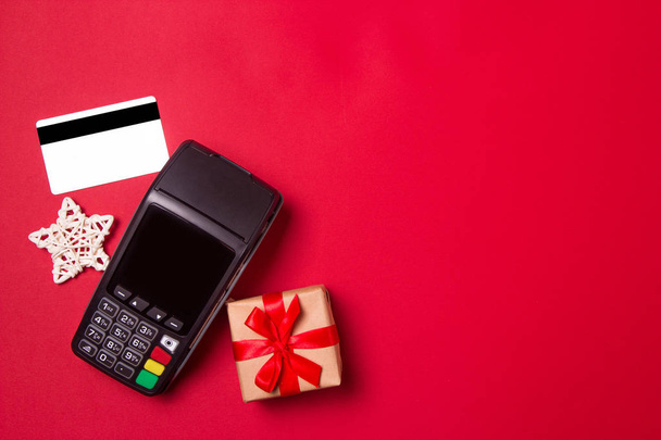 赤い紙の背景にクレジットカードとギフト付きの支払い端末。クリスマスセールコンセプト. - 写真・画像