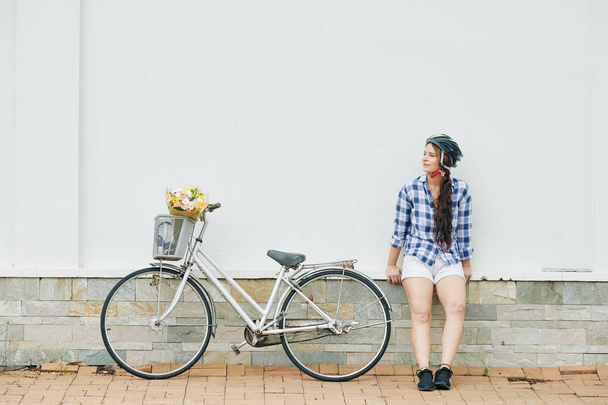 Νέα ενεργή γυναίκα κάθεται σε εξωτερικούς χώρους μετά την οδήγηση ποδήλατο στην πόλη και μελετώντας την ημέρα της  - Φωτογραφία, εικόνα