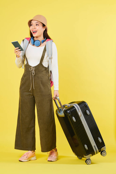 国際的なパスポートと大きなスーツケースを持つ興奮した若い女性旅行者は、別の国に飛ぶ準備ができて - 写真・画像