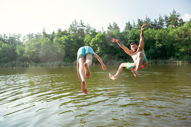 Happy friends having fun, ready to jump and swim in river - Foto, imagen