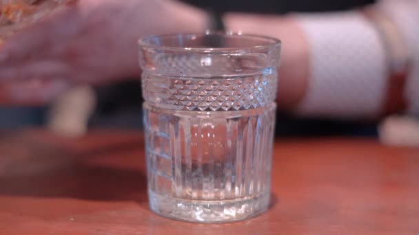 Barman Gentleman przygotowuje szklankę whisky z lodu sferycznego, formy lodu - Materiał filmowy, wideo