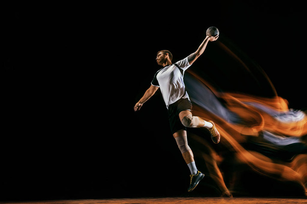 Young handball player against dark studio background in mixed light - 写真・画像
