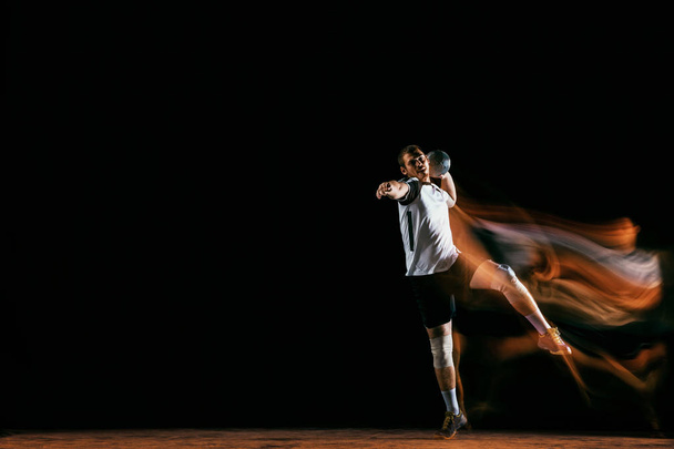 Young handball player against dark studio background in mixed light - Foto, immagini